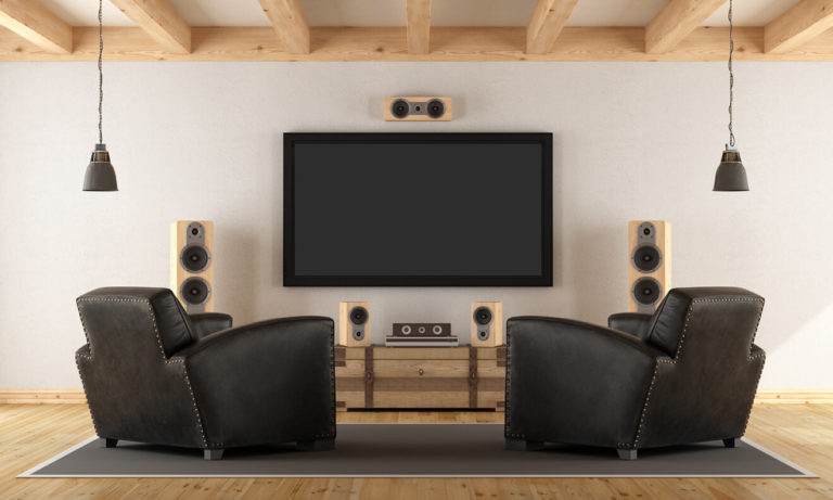 A custom disc & streaming home theater setup with two lounge chairs framing a large TV display, surrounded by amp speakers.